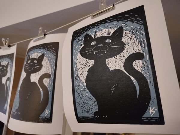 Three copies of a print depicting a cheeky cat.