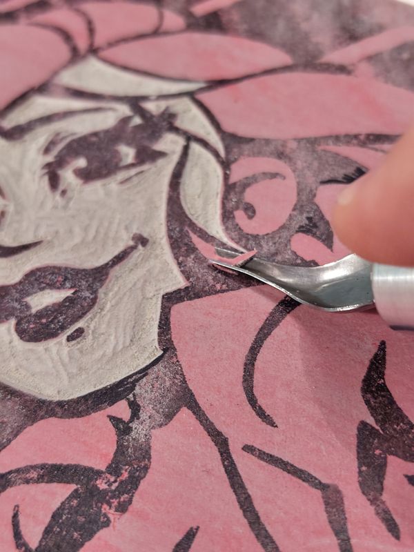 A closeup of cutting the linoleum block used for printing.